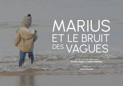 Extrait de l'affiche du film Marius et le bruit des vagues. On y aperçoit Marius de dos, les pieds dans l'eau face à la mer.